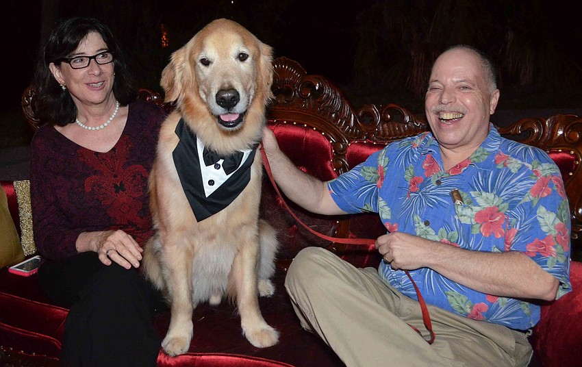 Gail and Ira Reiter laugh as they struggle to get a picture with Freddi, a 5-year-old golden retriever who serves as a therapy dog in the Child Protection Center’s P.A.W.S. Animal Advocates program.