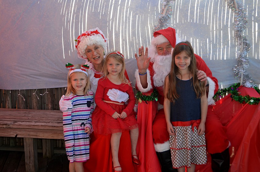 Ally Hagan, 5, and Brynn, 5, and Camryn Shear, 8 visit with Santa and Mrs. Claus.