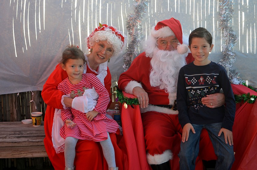 Samantha and Alex Carmona, 3 and 9, sit with Santa and Mrs. Claus.