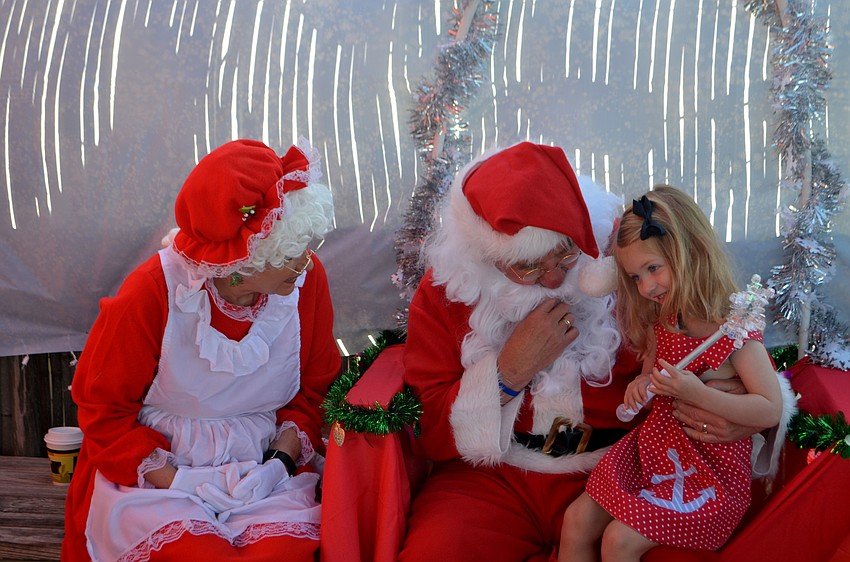 Olivia Rowley, 3, talks with Mrs. Claus and Santa Claus.