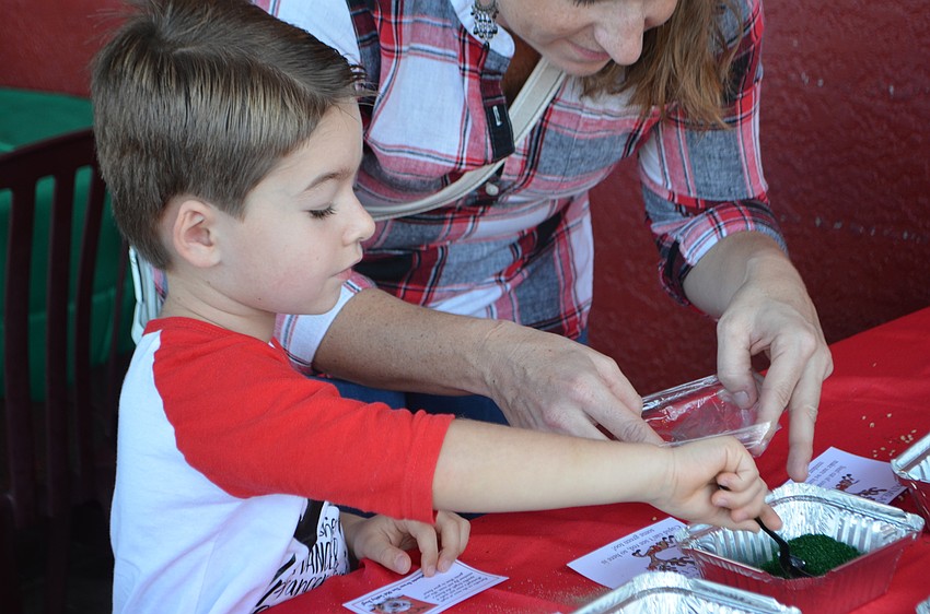 Brandon Parrish, 4, makes a bag of reindeer food. Cards on the table told kids which items some of the reindeer liked best.