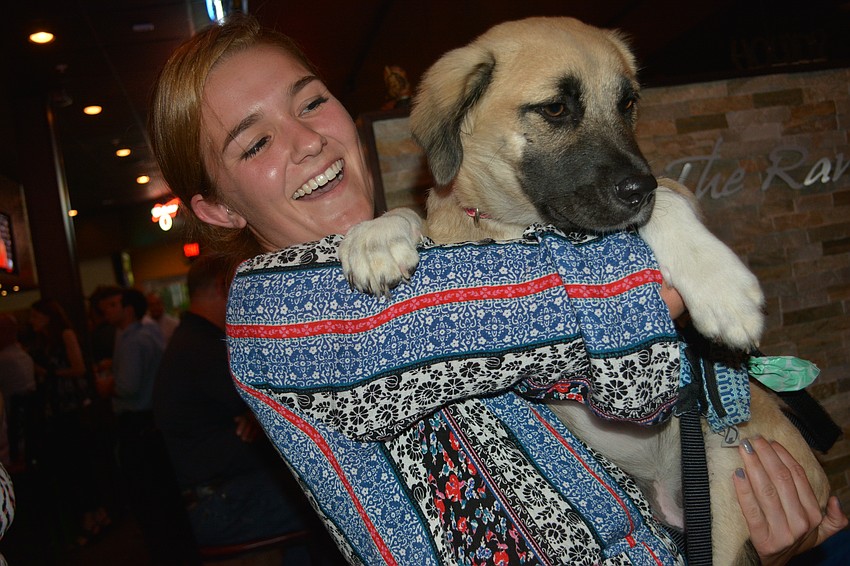 Audrey Reinisch hugs her dog, Ellie, a 5-month-old shepherd mix she adopted from Nate's Honor Animal Rescue. Reinisch is a kennel technician for Nate's.