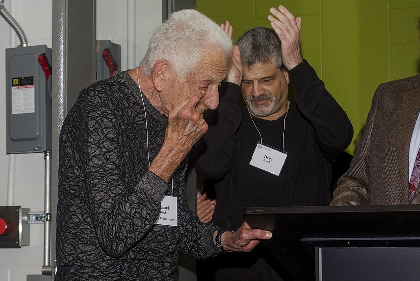 Richard Basch wipes a tear from his eye after receiving an honorary doctorate from Ringling College of Art and Design as his son, Dane Basch, claps.