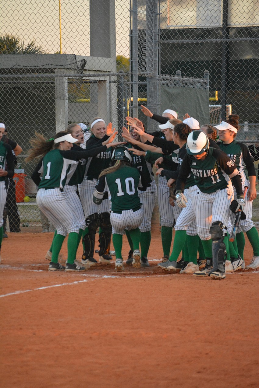 The Mustangs greet Kinsey Goelz at home plate after her home run.