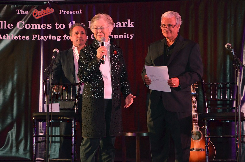 Executive Vice President of the Orioles John Angelos and emcee Jim Hunter listen to Isabel Norton of the Library Foundation for Sarasota County Board of Directors thank attendees at the event on March 17 at Ed Smith Stadium.