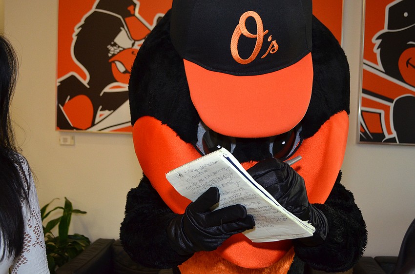 The Oriole Bird writes its name down on an Observer notepad  at Nashville' s Music Row Comes to the Ballpark on March 17 at Ed Smith Stadium.