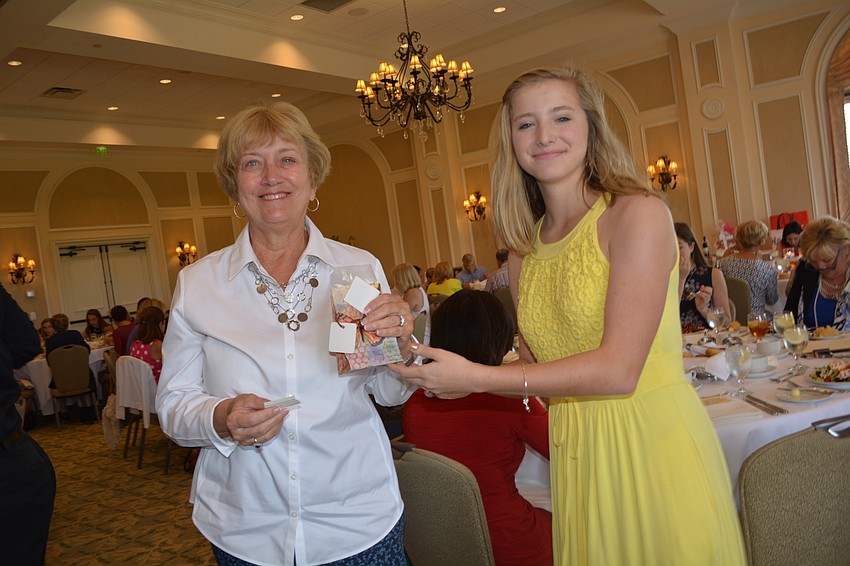 Janet Hough won an Alex and Ani brand lobster charm bracelet from the silent auction. Carli Kasten, who suffers from Cystic Fibrosis, hands out the prizes.