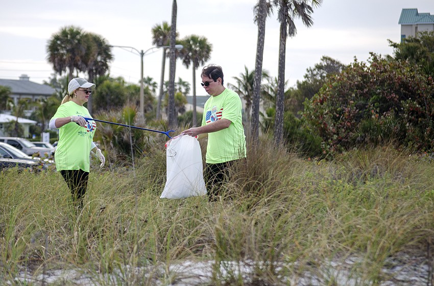 Gisel Sanchez and Rodolfo Perez pick up trash on Lido Beach.