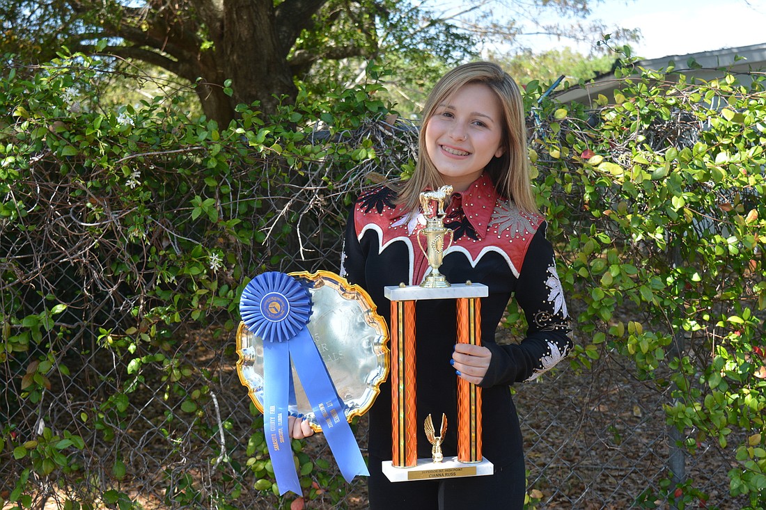 Cianna Russ poses with her 2015 National Reserve Championship trophy in showmanship and a Superior Intermediate High Point Championship trophy.