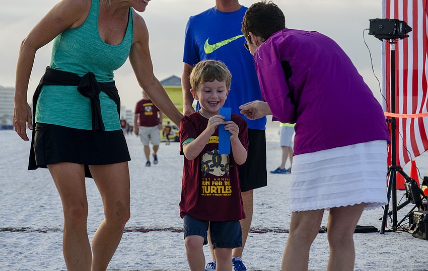 Colton Davenport is awarded a ribbon for finishing the one-mile children' s fun run.