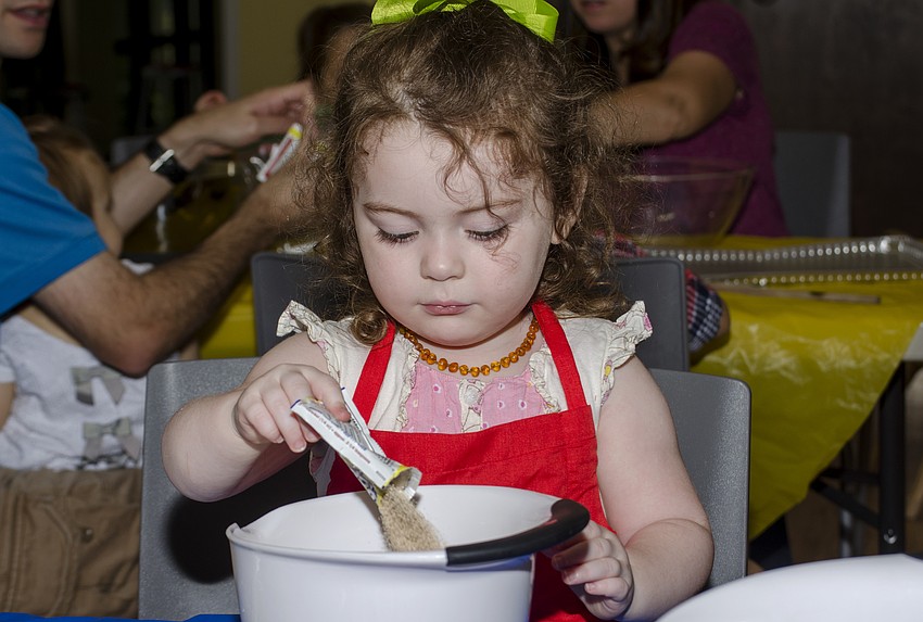 Sasha Leopold pours yeast into a mixing bowl at the challah workshop at Temple Emanu-El.