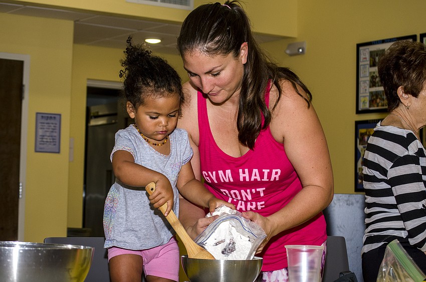 Eliana and Pamela Lasko pour flour into a mixing bowl at the challah workshop at Temple Emanu-El.