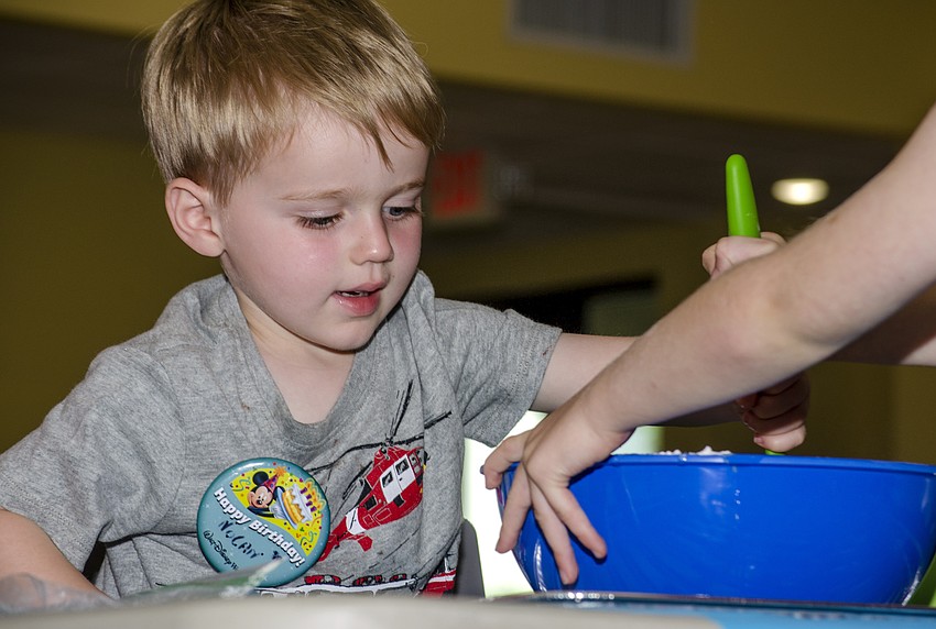 Nolan Duffy stirs his family' s challah dough at the challah workshop at Temple Emanu-El.