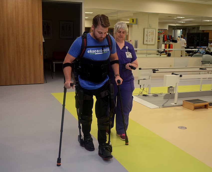 Shane Mosko and Kim McClowghan demonstrate how the EKSO Skeleton works. Mosko is paralyzed from the waist down, with some movement, but this equipment helps him walk around and improve muscle movement.