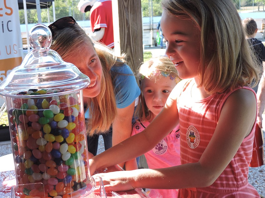 Michelle and Sami Bransfield watch as Alex Bransfield takes a guess at how many jellybeans are in the jar at the East County  Observer' s game table.