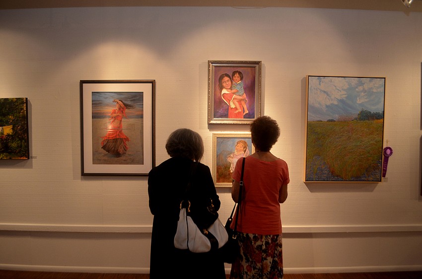 Erma Nussbaum and Madelaine Ginsberg stop and look at various paintings on display at the Women Contemporary Artists exhibit.
