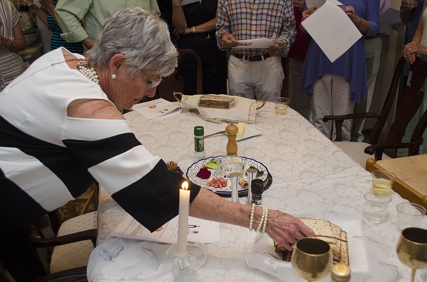 Susan Masters breaks the matzah bread during the Passover seder at the Straff Passover Party on April 10 at the home of Roberta and Larry Straff.