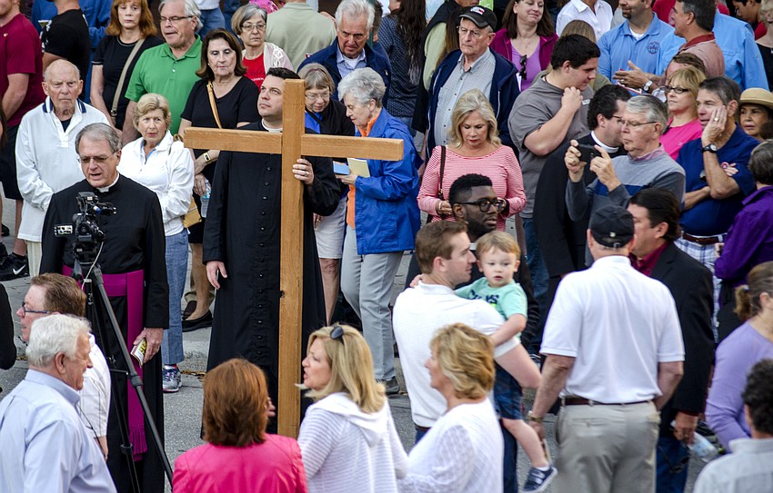 Rev. Chris Wood holds the cross as participants mingle outside Regal Hollywood Stadium 20 on Main Street before the beginning of the walk.