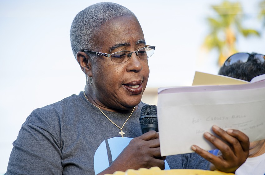 Carolyn Mason leads the processional in a prayer at the first station of the cross at the intersection of Links Avenue and Main Street.