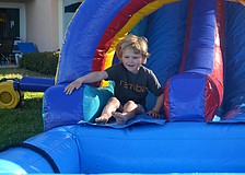 Stone Flood, 5, takes a turn slipping down the inflatable water slide at Sand Cay’s Easter Egg Hunt.