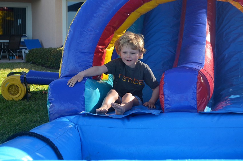 Stone Flood, 5, takes a turn slipping down the inflatable water slide at Sand Cay’s Easter Egg Hunt.