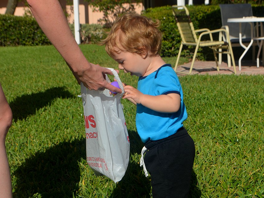 Jay Pequignot, 16 months, puts his eggs in a baf during Sand Cay’s Easter Egg Hunt on April 14.