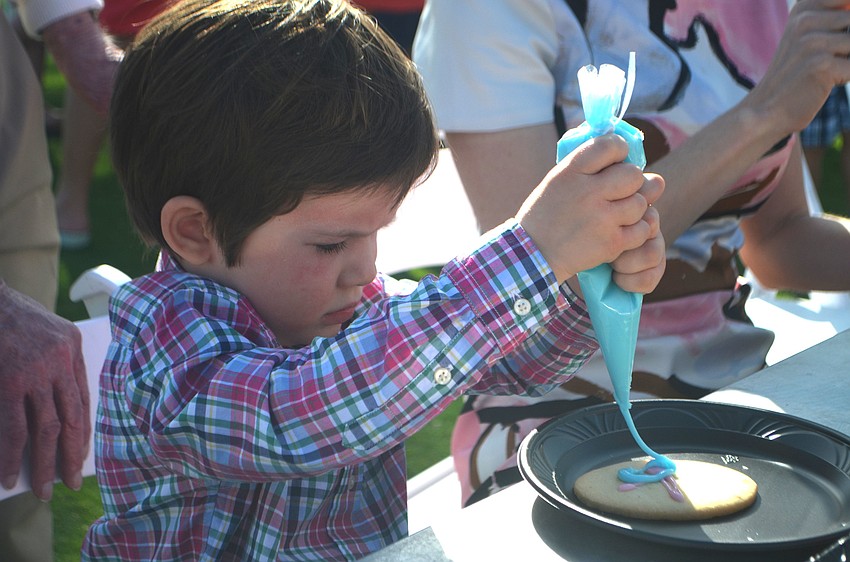 Collin Huber, 2 ½, decorates an Easter egg-shaped cookie before the egg hunt at the Longboat Key Club on April 16.