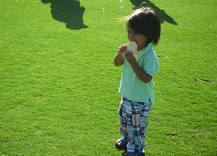 Rory Rasool, 2, munches on a cookie and watches bubbles float by at the Longboat Key Club’s Easter celebration on April 16.