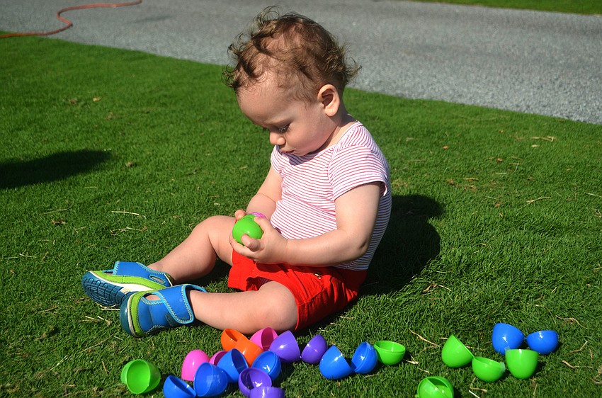 Oliver Lane, 1, plays with the Easter eggs he found during the Longboat Key Club’s egg hunt.