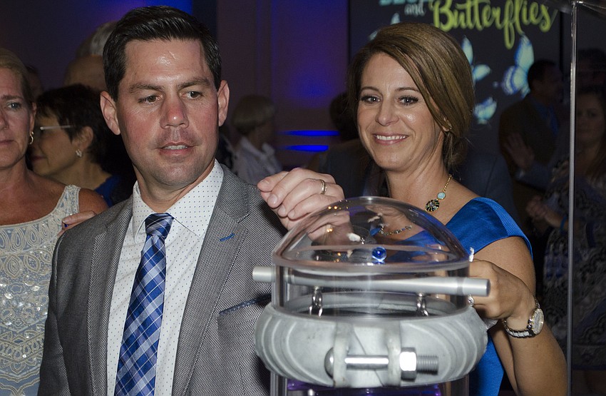 Mike and Tina Granthon watch as their marble descends down the mini pillar of hope at the end of Blue Ties and Butterflies on April 19 at Michael’s On East.