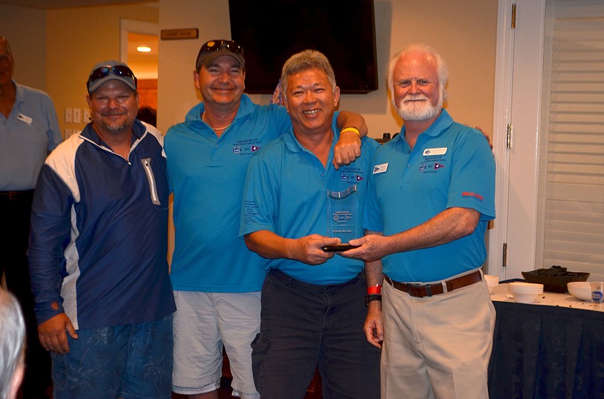 Tung Nguyen and crew accept the award for first place in the multihull division of the PHRF Course from Mote President and CEO Michael Crosby.