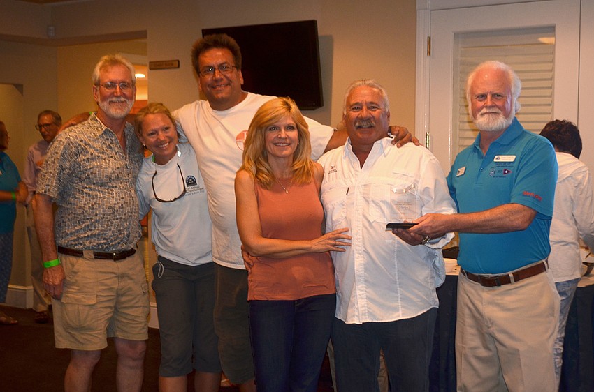 Richard Gress and crew accept the award for second place in the spinnaker division of the PHRF Course from Mote President and CEO Michael Crosby.