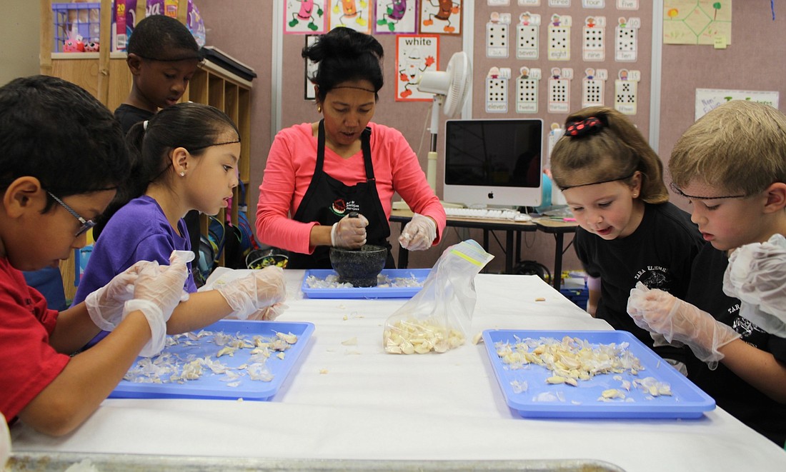 Tara Elementary School kindergarten teacher Josephine Johnson shows her students how to prepare garlic cloves for cooking.