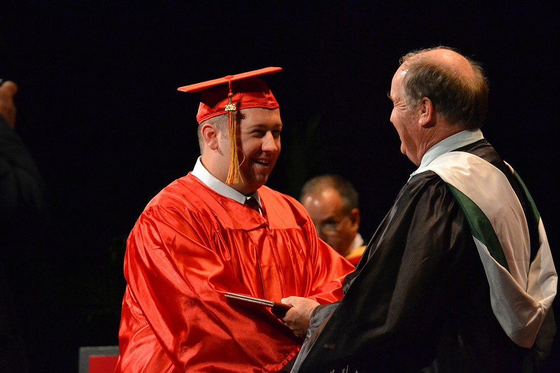 Quinn Campbell receives his diploma from Principal Steve Christie at Cardinal Mooney High School&#39;      s 2016 graduation.