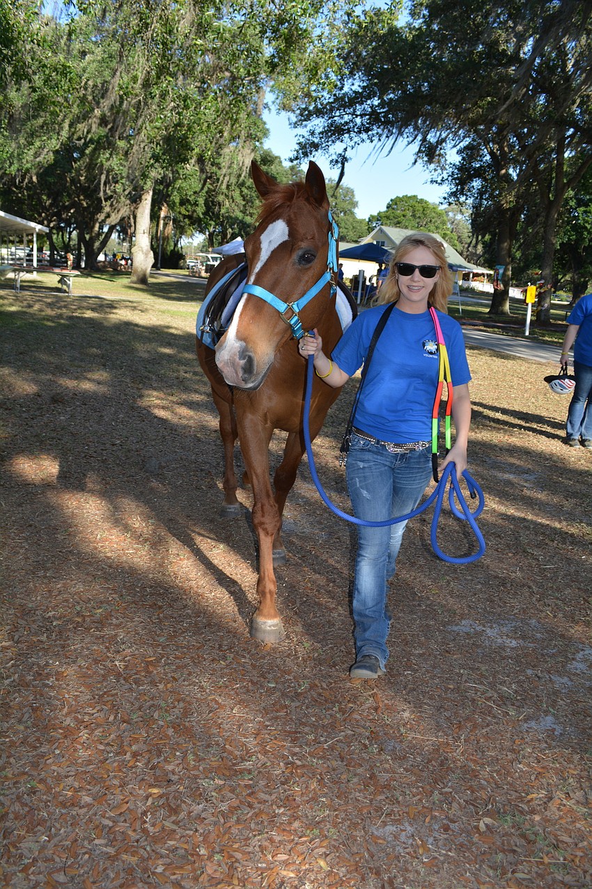 SMART volunteer Megan Jones leads in therapy horse Cherokee following the Parade of Champions by SMART riders.