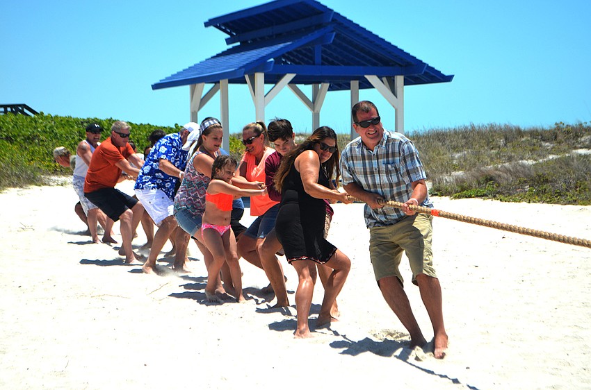 The police department teams pulls as hard as they can in the tug of war match against the fire department.