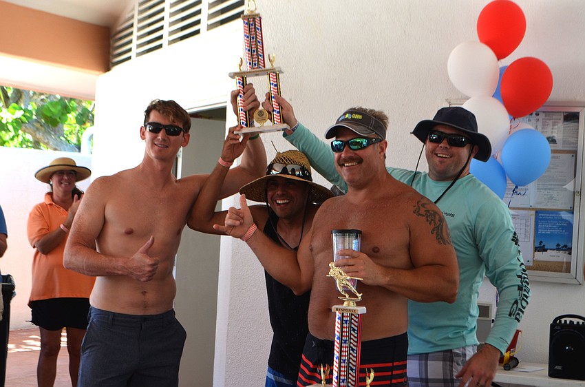 The fire department volleyball team raises their trophy high during the program.