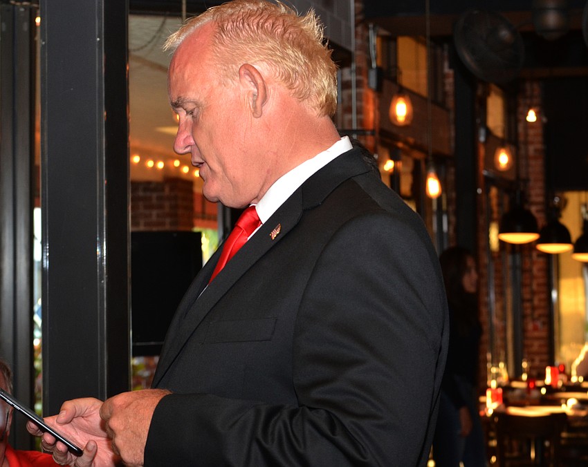 Martin Hyde checks results on his phone during his watch party at Caragiulo’s.