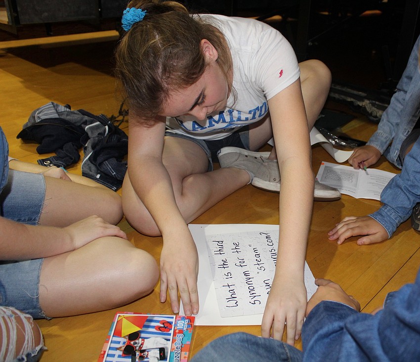 Braden River Middle School seventh grader Sofia Figueras reads the message on the back of a puzzle aloud to her STEAM team.