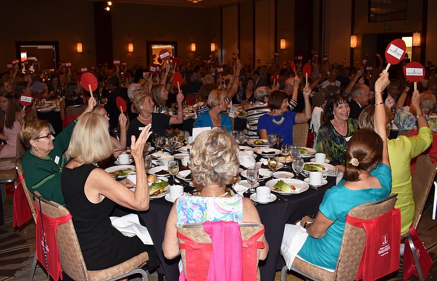 Junior League of Sarasota members raise their paddles at the Junior League of Sarasota Annual Dinner on May 16 at Hyatt Regency Sarasota to show how many women participated in service projects this year.