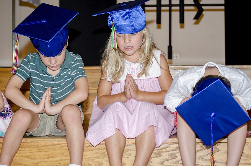 Zaile Fasbinder, Audrey Wallin and Sebastian Oswald pray during the graduation ceremony at St. Boniface Preschool.