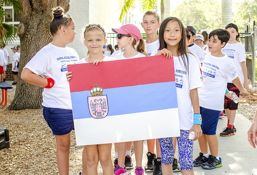 Clara Plass and Mischa Doan hold the Serbian flag as they lead their class in the parade of nations.