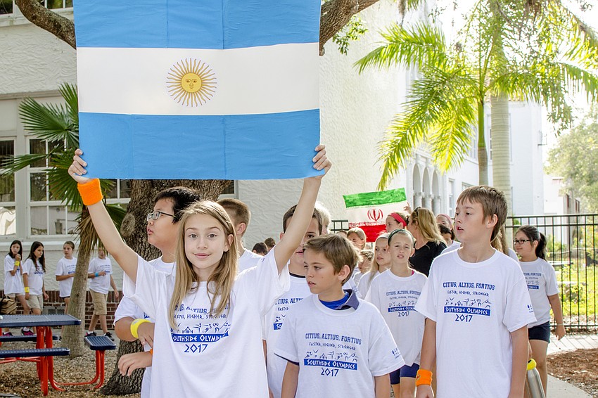 Charlie Anne Gullick holds the Argentinian flag while leading her class in the parade of nations.