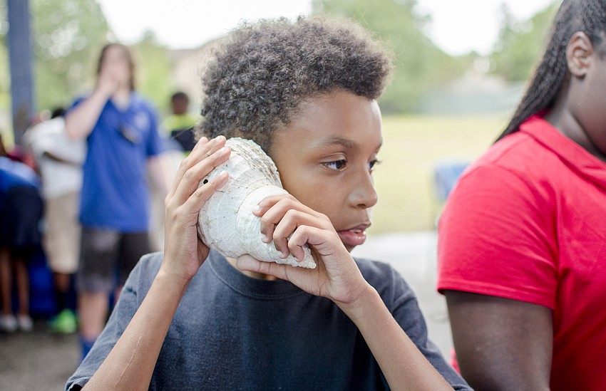 Tishod listens to a sea shell during the Mote presentation that followed the ribbon cutting.