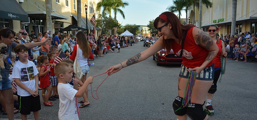 Sarah Bikos of the Bradentucky Bombers Roller Derby team reaches out to Lakewood Ranch'   s Wayne Comegno, 5, who gets some beads.