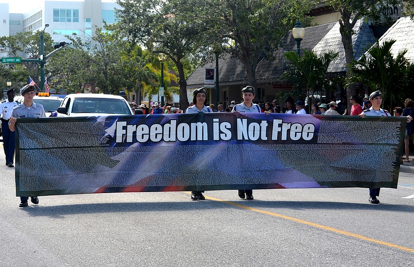 Sarasota Military Academy cadets carry the “Freedom is Not Free” banner down Main Street. The banner has the names of fallen military members printed on it.