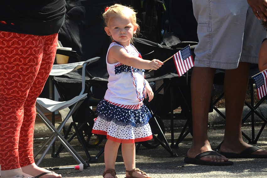 London Thacker waves her flag as the parade marches down Main Street.