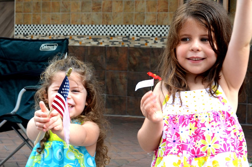 Cora and Zoe Baszner wave their flags as the parade makes it way down Main Street to J.D. Hamel Park.