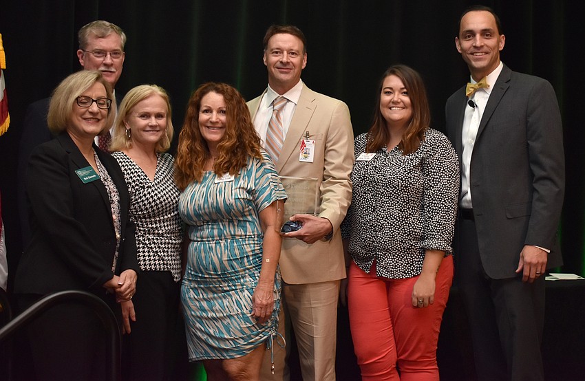 Beth Ebersole, Steve Branham, Jayne Giroux, Pam Foster, Suncoast Blood Bank CEO Scott Bush, Bailey Christie and Chamber President and CEO Kevin Cooper pose with the award for Non-Profit Organization of the Year.