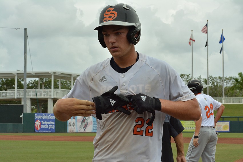 Brooks Larson takes off his batting gloves after making an out.